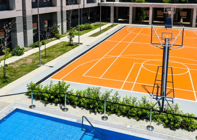 an orange basketball court with a pool in the background